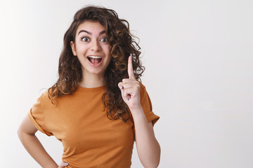Girl have excellent idea. Portrait excited happy young woman share thoughts raise index finger eureka gesture smiling open mouth telling us awesome plan standing white background thrilled - obrazy, fototapety, plakaty