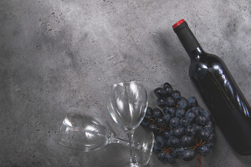1 bottle of red wine, dark grapes, 1 glass on a gray background copy space,