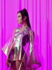 Cyberpunk and neon, a young trend girl in a transparent latex raincoat.