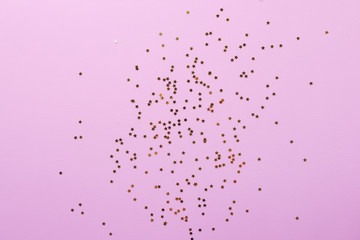 Pink background studded with gold sparkling star shaped glitter confetti. Birthday, valentines, christmas celebration concept