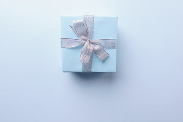 Present box in wrapping paper and tied with satin ribbon on blue background, copy space. Father's day, birthday, Valentine' s day gift