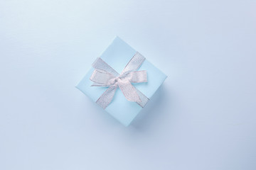 Presents, holiday traditions and shopping. Gift box in wrapping paper and tied with satin ribbon on blue background, copy space