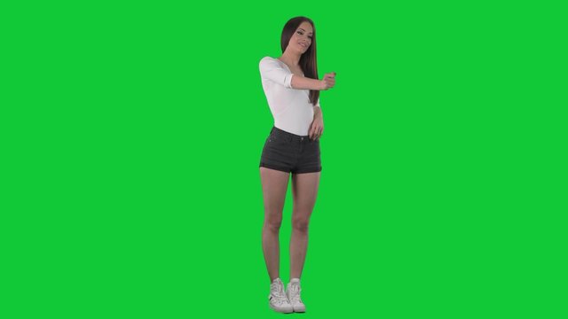 Beautiful casual young woman offering handshake as good deal. Look away and to camera. Full body over green screen background. 