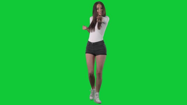 Beautiful young funny playful woman doing judo or karate fighting poses and punches. Full body over green screen background. 