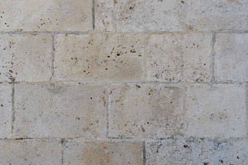 Fragment of an old stone wall of an ancient Roman temple made of processed sandstone. Background. Gray.