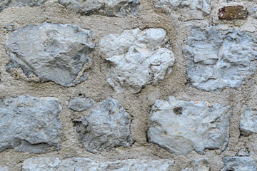 A fragment of an old stone wall made of rough stones. Background. Gray.