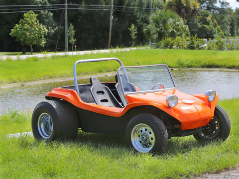 An orange beach buggy car front a lake.