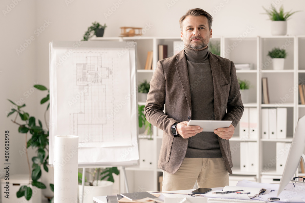 Poster Architect with tablet standing by desk on background of sketch on whiteboard