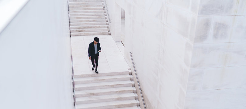 Young man going down stairs while using smartphone