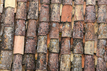 A fragment of an old tiled roof covered with mold and traces of time. Aged shingles. Background. Pattern. Terracotta. Gray. Ocher.