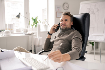 Fototapeta premium Serious mature businessman or agent consulting clients by desk in office