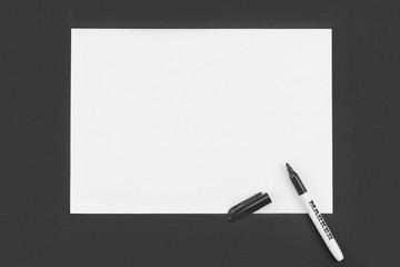 Black marker with blank white paper on black background. Mock-up with place for your text, ideas. Flat layout, top view.
