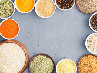 Oat, millet, green cardamom, allspice, cumin, pepper chili, fenugreek, turmeric, cloves, masala, mustard seeds, dry ginger on gray concrete background. Indian cuisine, ayurveda, naturopathy concept