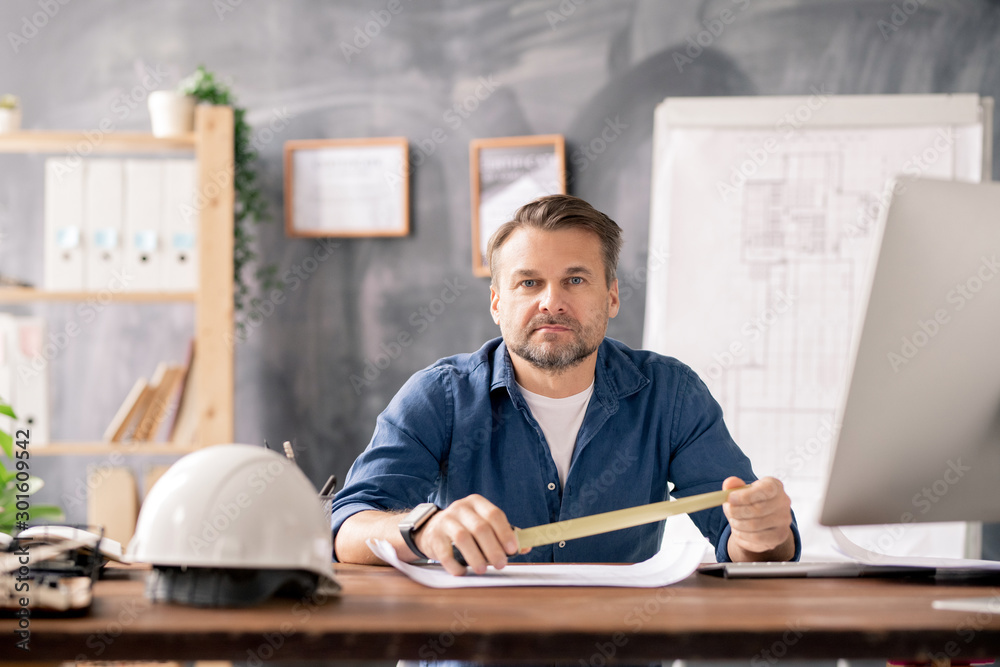 Aufkleber confident engineer holding measuring tape over blueprint while sitting by table