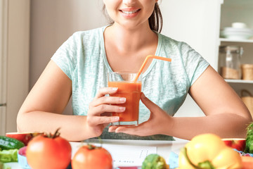 Obraz na płótnie Canvas Body Care. Chubby girl sitting at kitchen table with glass of detox smoothie smiling cheerful close-up