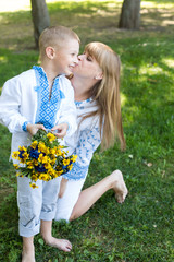 Fototapeta premium mother and son in embroidered shirts. national clothes of Ukraine. a boy gives flowers to his mother