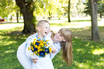 mother and son in embroidered shirts. national clothes of Ukraine. a boy gives flowers to his mother