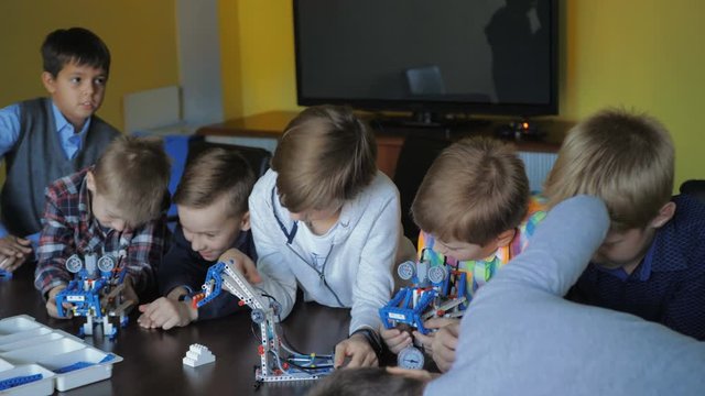 Children in the classroom make figures with teacher. Modern technology concept