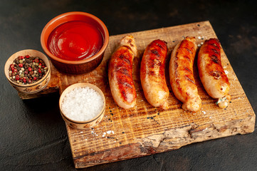 Grilled sausages with spices, ketchup and rosemary on a stone table, ready to eat