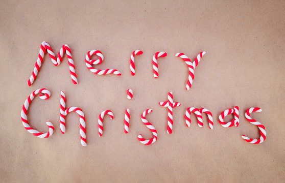 Colorful Merry Christmas on packing paper. Letters are red and white candy canes made of clay.