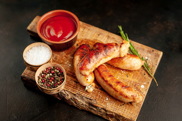 Grilled sausages with spices, ketchup and rosemary on a stone table, ready to eat