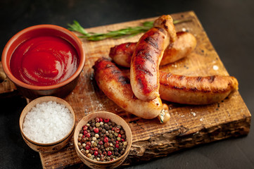 Grilled sausages with spices, ketchup and rosemary on a stone table, ready to eat