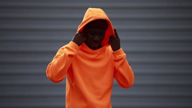 Handsome cool African man model wearing bright orange hoodie and hat