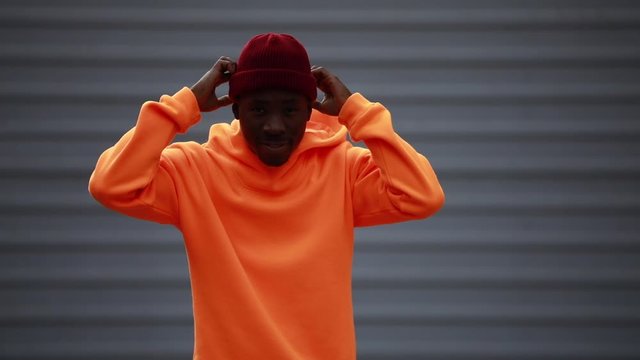 Handsome cool African man model wearing bright orange hoodie and hat