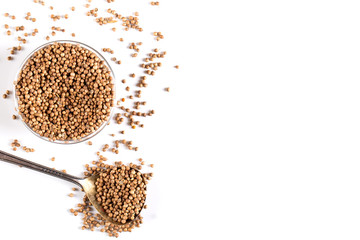 Coriander grains in a wooden spoon on a white background. Concept, copy space.