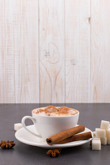 Cup of coffee with marshmallows and cocoa, sugar, cinnamon and star anise, on a gray stone background.