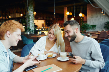 Clever guy making presentation to friends while preparing for seminar in cafe