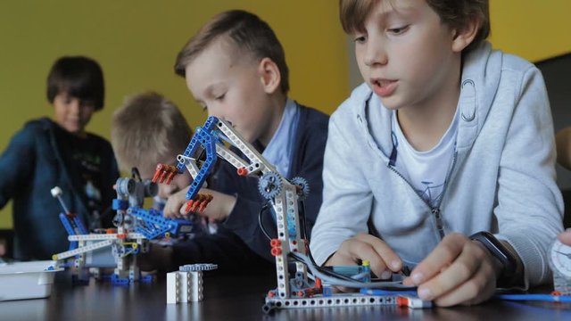 Children in the classroom make figures with teacher. Modern technology concept