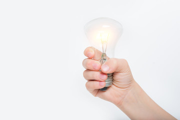 Glowing incandescent lamp in a child's hand on a light background