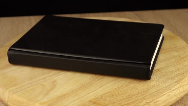 black notebook rotates 360 degrees on wooden platform