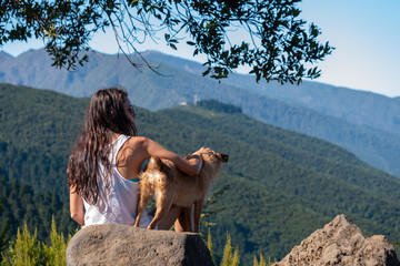 young girl looks at the landscape with her dog