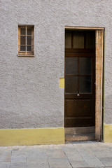 Haustür mit offener zusammengeschobener Scherengittertür als Schutz vor Einbruch neben einem kleinen vergitterten Fenster