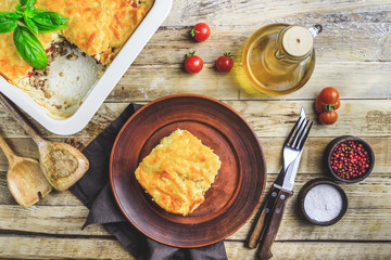 Delicious meat casserole with eggplant, minced meat, tomato, bechamel sauce and cheese. Greek moussaka on rustic wooden background. Top view