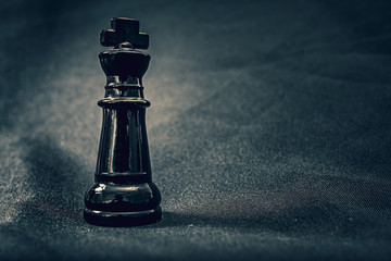 black glass King chess piece on dramatic background