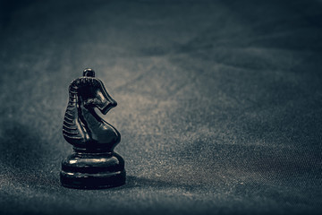 Glass black knight chess piece on dramatic background