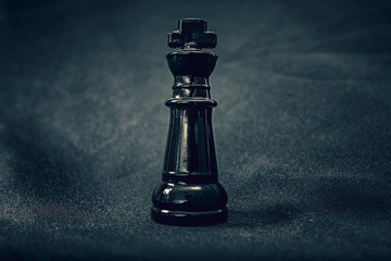 Fototapeta na wymiar black glass King chess piece on dramatic background