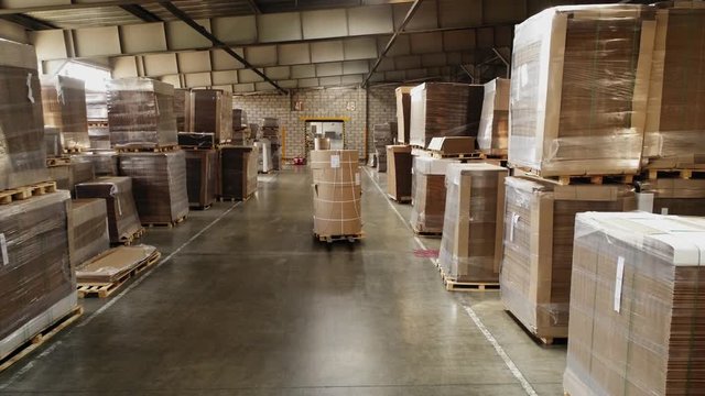 forklift loaders carry paper rolls along pathway in storage