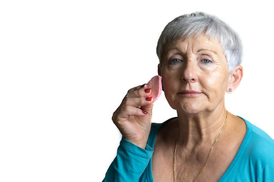 older White haired woman smiling with makeup sponge in her hand on isolated White backhground