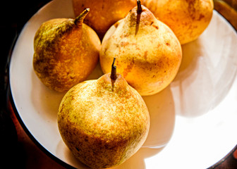  Fresh yellow pears lie on gray boards in a white plate.  Useful fruit for vegan and Keto diet.
