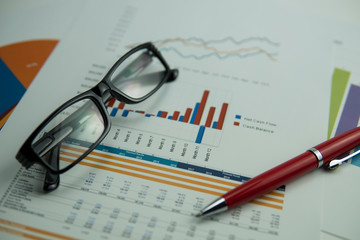 Selective focus of chart graph document with eye glasses and pen on top. Showing report by monthly with statistic graph.