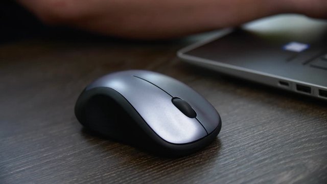 man works on laptop using wireless mouse at table closeup