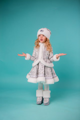 little blonde girl smiling in snow maiden costume isolate on blue background, baby catches snowflakes