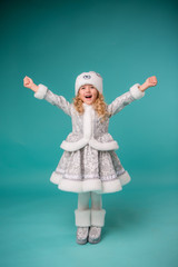 little blonde girl smiling in snow maiden costume isolate on blue background, baby catches snowflakes