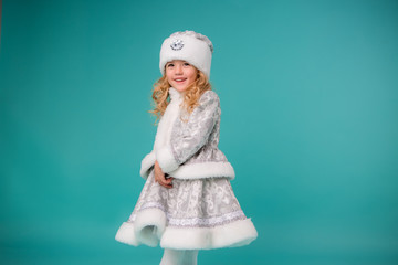 little blonde girl smiling in snow maiden costume isolate on blue background, baby catches snowflakes