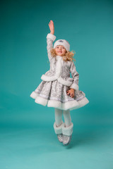 little blonde girl smiling in snow maiden costume isolate on blue background, baby catches snowflakes