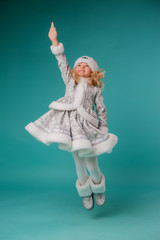 little blonde girl smiling in snow maiden costume isolate on blue background, baby catches snowflakes